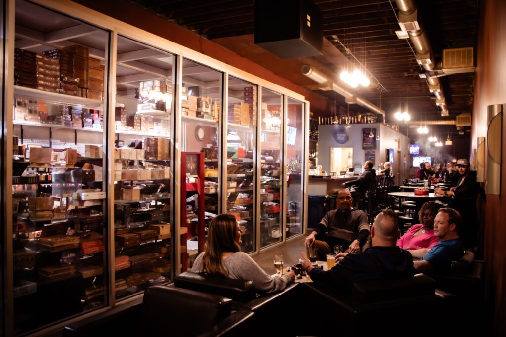Guests in lounge chairs next to the glass-front humidor at Classic Cigars